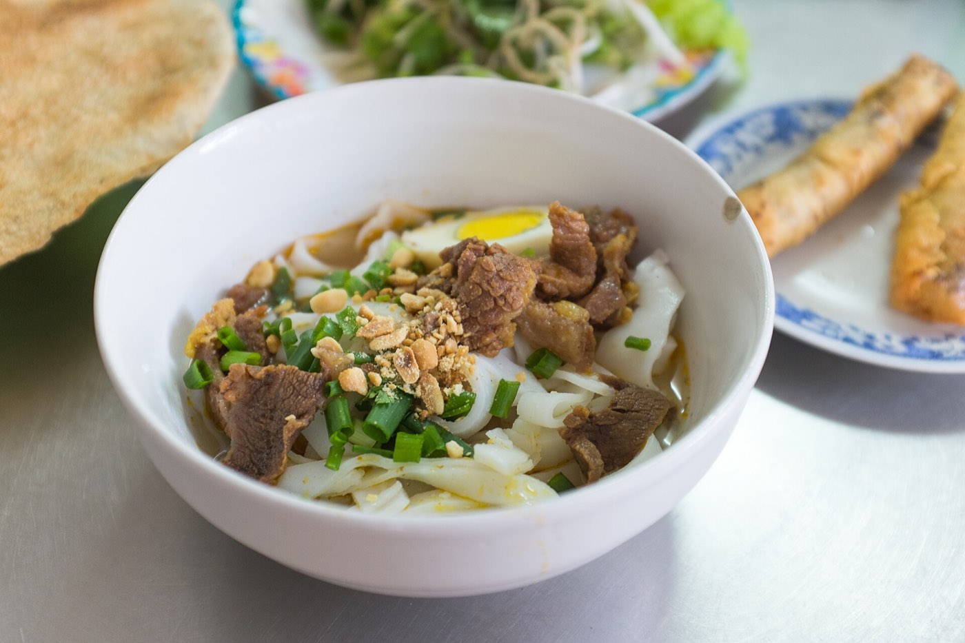 Mi Quang, turmeric-yellow noodles with peanuts, herbs and a sesame cracker